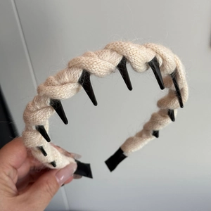 Detail of cable knit headband in beige with black punk studs and textured wool