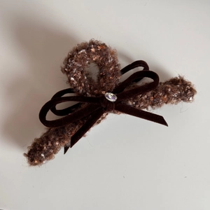 Détail de la pince à cheveux marron en bouclée avec un nœud en velours et un strass