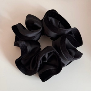 Détail d'un chouchou en velours et satin noir avec volants et texture douce
