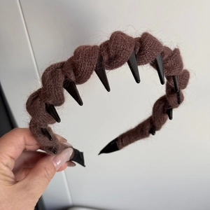 Detailed view of brown knit headband featuring punk-style black spikes and twist texture