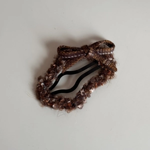 Gros plan sur la barrette à nœud en tweed marron avec texture tissée et détails élégants