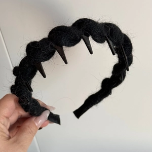 Close-up of black knitted twist headband featuring inner plastic comb teeth for grip