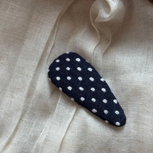Detailed view of polka dot fabric BB hair clip with white embroidery on black cotton base
