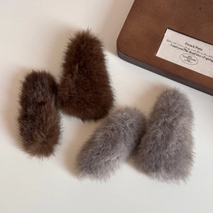 Detailed view of plush triangle hair clips in dark brown and light gray faux fur