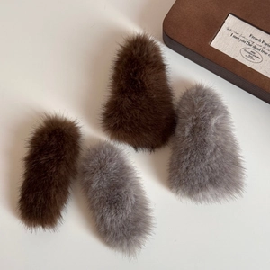 Detailed view of four fluffy faux fur hair clips in brown and grey for autumn and winter