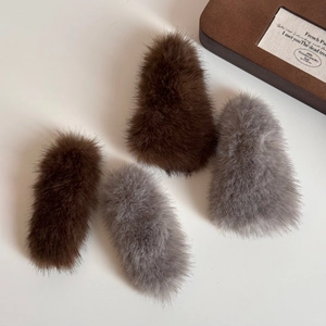 Detail of plush faux fur hair clips in brown and grey colors on white background