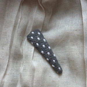 Close-up of handmade dark grey woven BB hair clip with white polka dot embroidery details