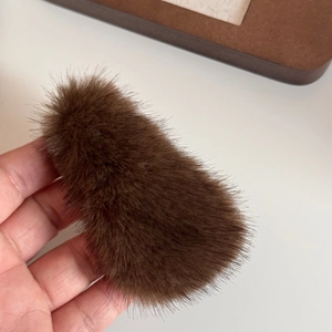 Detail shot of a plush dark brown triangle hair clip showing soft faux fur texture