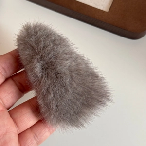 Macro shot of gray plush triangle hair clip showing soft faux mink fur texture