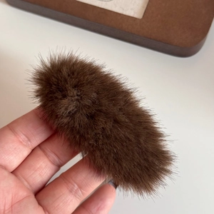 Close-up of brown plush triangle hair clip showing soft faux fur texture and detail