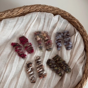 Handmade knitted yarn hair clips in gradient colors set on a rustic woven tray