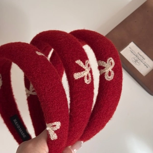 Red plush headband with white embroidered bow and handmade label for elegant hair styling
