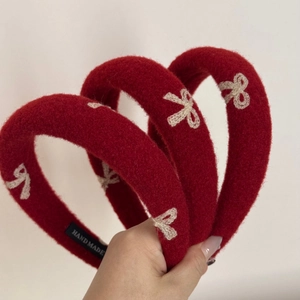 Close-up of red velvet headbands featuring white butterfly embroidery and hand made label