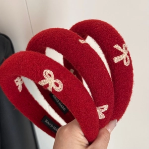 Close-up of red velvet headbands with white bow embroidery and handmade cloth labels