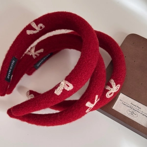 Detailed macro view of handmade red embroidered bow headband with woven logo label