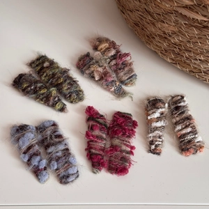 Close-up of five pairs of colorful handmade knitted wool hair clips in various autumn colors