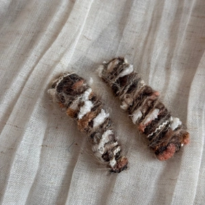 Close-up of multicolor wool-wrapped hair clips with handcrafted fuzzy texture and fabric background