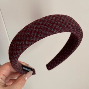 Detail showing the red houndstooth fabric texture and handmade label of the padded headband