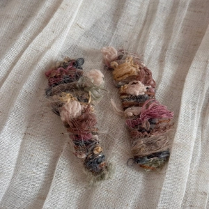 Detail of handmade gradient wool knitted hair clips on a soft white linen background