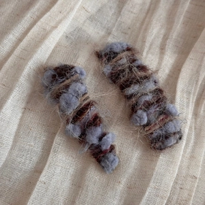 Close-up of textured autumn wool hair clips with colorful gradient yarn on beige fabric