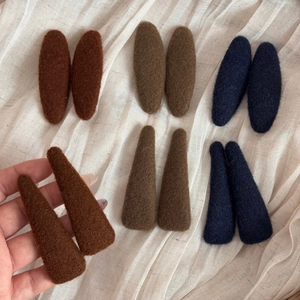 Detailed texture of felt autumn hair clips in brown and navy blue tones on white fabric