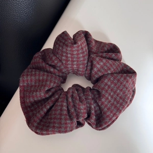 Close-up of red and grey houndstooth plaid fabric hair scrunchie with thick texture