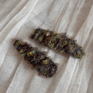 Macro detail of plush wool knitted hair clips in autumn gradient colors on linen