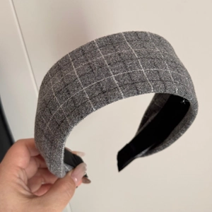 Detail showing grey plaid fabric headband with thick wool texture and black inner lining