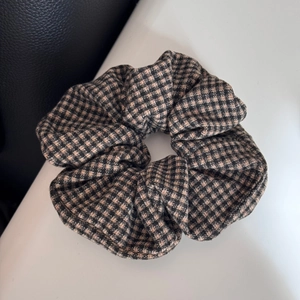 Close-up of brown and black houndstooth pattern fabric scrunchie with pleated texture