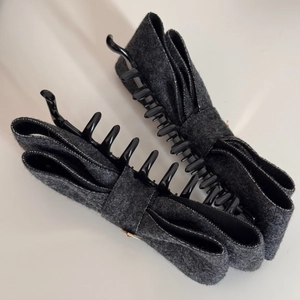 Dettaglio di fermagli per capelli in tweed grigio con fiocco e clip a banana con denti lunghi