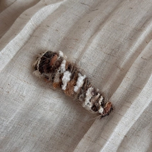 Macro detail of hand-knitted wool hair clip in warm gradient brown and white tones