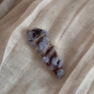 Detail of wool knit hair clip featuring brown and blue textured gradient yarn weave