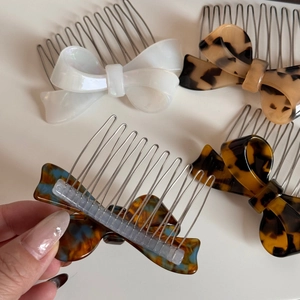 Detail of acetic acid bow hair comb featuring tortoise shell patterns and metal teeth