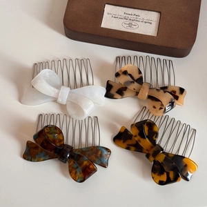 Detail of four acetate bow hair side combs in marble and tortoiseshell patterns