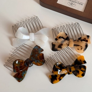 Set of four bow-shaped acetate hair side combs in pearl white and various tortoiseshell patterns