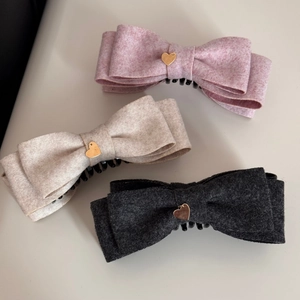 Dettaglio di fermagli per capelli con ciondoli a cuore in rosa, beige e grigio
