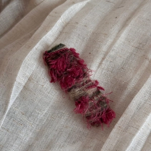 Detailed texture of gradient woolen hair clip on a natural beige linen fabric background