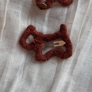 Detailaufnahme der gestrickten Hunde-Haarspangen in Karamelbraun mit Love-Anhänger