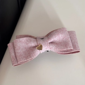 Dettaglio del fermaglio per capelli in tweed rosa con ciondolo a cuore dorato per capelli