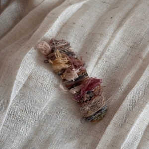 Detailed shot of multi-color wool yarn wrapped snap hair clip on rustic linen fabric