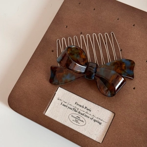 Detail view of tortoise shell acetate bow hair comb with elegant gold metal teeth