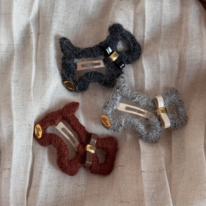 Detailansicht von drei gestrickten Welpen-Haarspangen mit goldenen Love-Anhängern