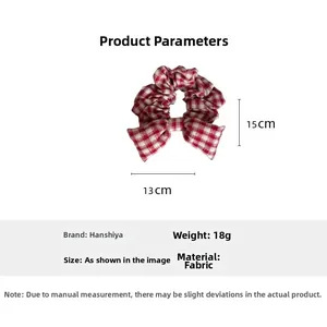 Detail view of red plaid bow hair scrunchie showing 13cm width and 15cm height dimensions