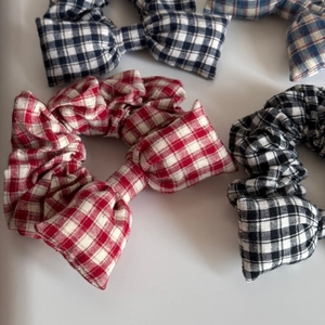 Detail of checkered bow hair scrunchies in red, black, and blue plaid patterns