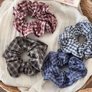 Chic vintage plaid scrunchies in four colors displayed on white fabric and basket