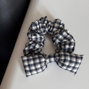 Close-up of black and white plaid bow scrunchie showing fabric texture and checkered pattern