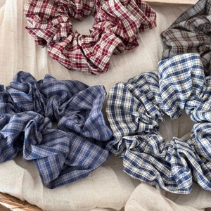 Close-up of vintage plaid scrunchies in various colors displayed in a woven basket