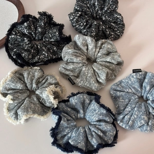 Detail of six knitted scrunchies with woven textures and fashion labels on neutral background