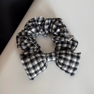 Close-up of black and white gingham bow scrunchie with detailed fabric texture