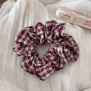 Detail of red and white checkered scrunchie with natural cotton texture on linen